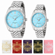 Relojes de pareja Invicta 48906 y 48907 plateados con correa multieslabón y esferas azul claro, junto a cinco cajas de mini perfumes Lattafa sobre fondo blanco.